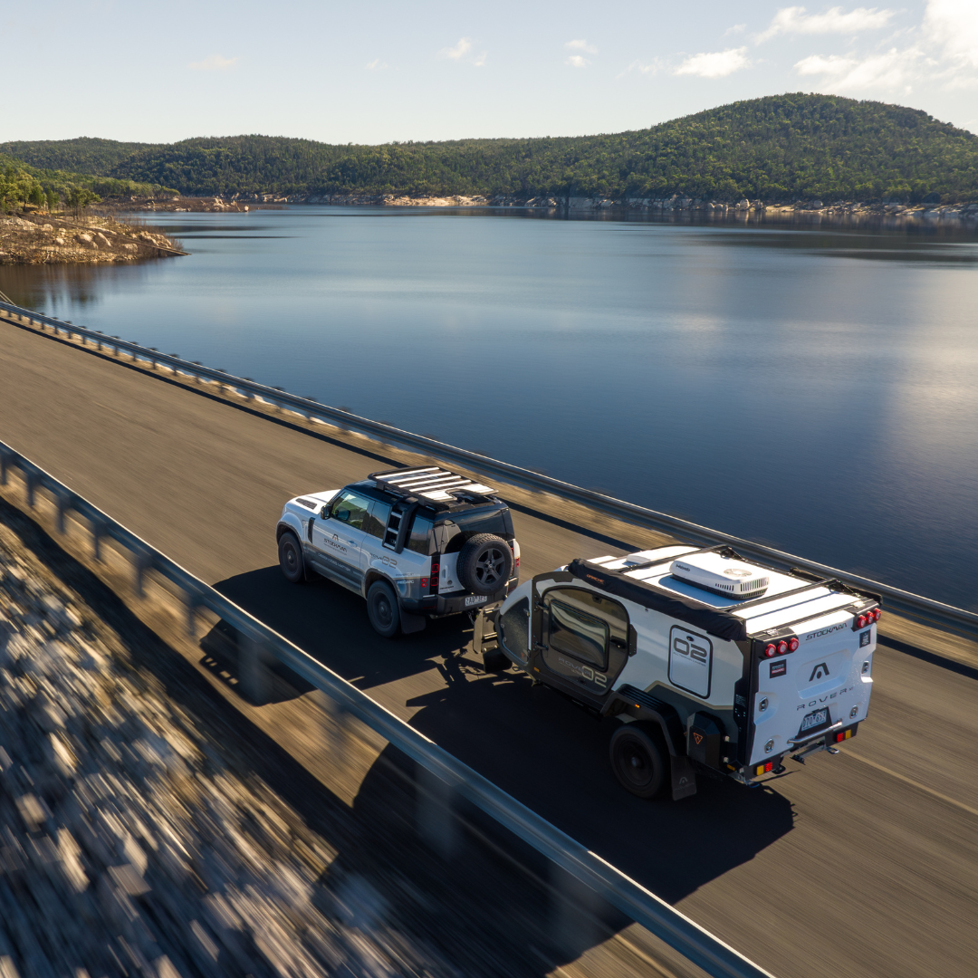 Stockman camper towed along a coastal road beside the water