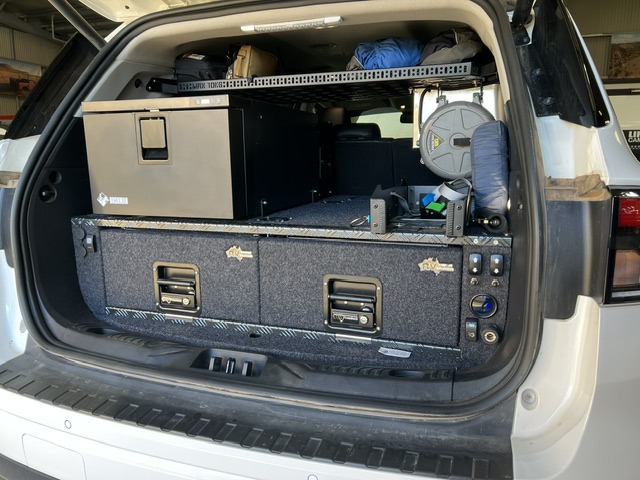 Rear storage setup - of a Ford Everest with aluminium storage drawers, Bushman fridge, overhead shelf, 12V oven, air hose reel, airbag controls and onboard air compressor.