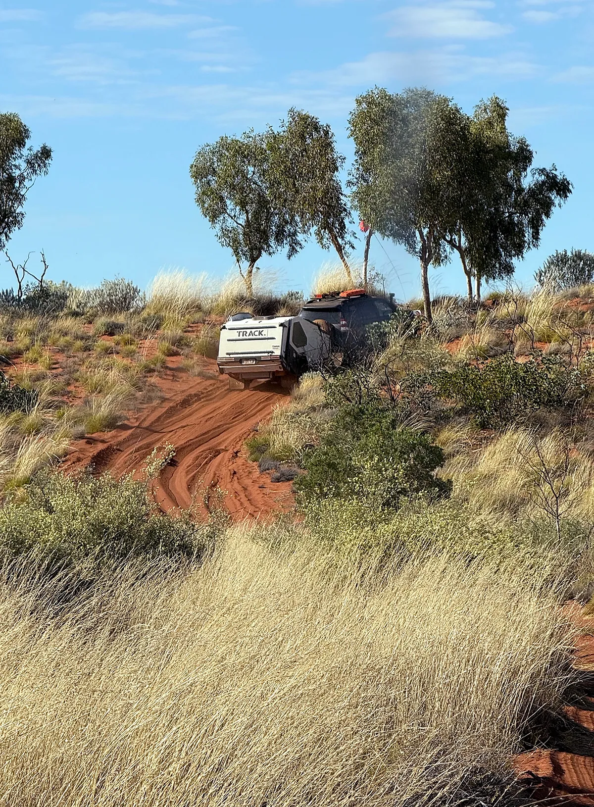 Towing a Track Trailer Tvan along a narrow red track bordered by tall grass, scrub and trees