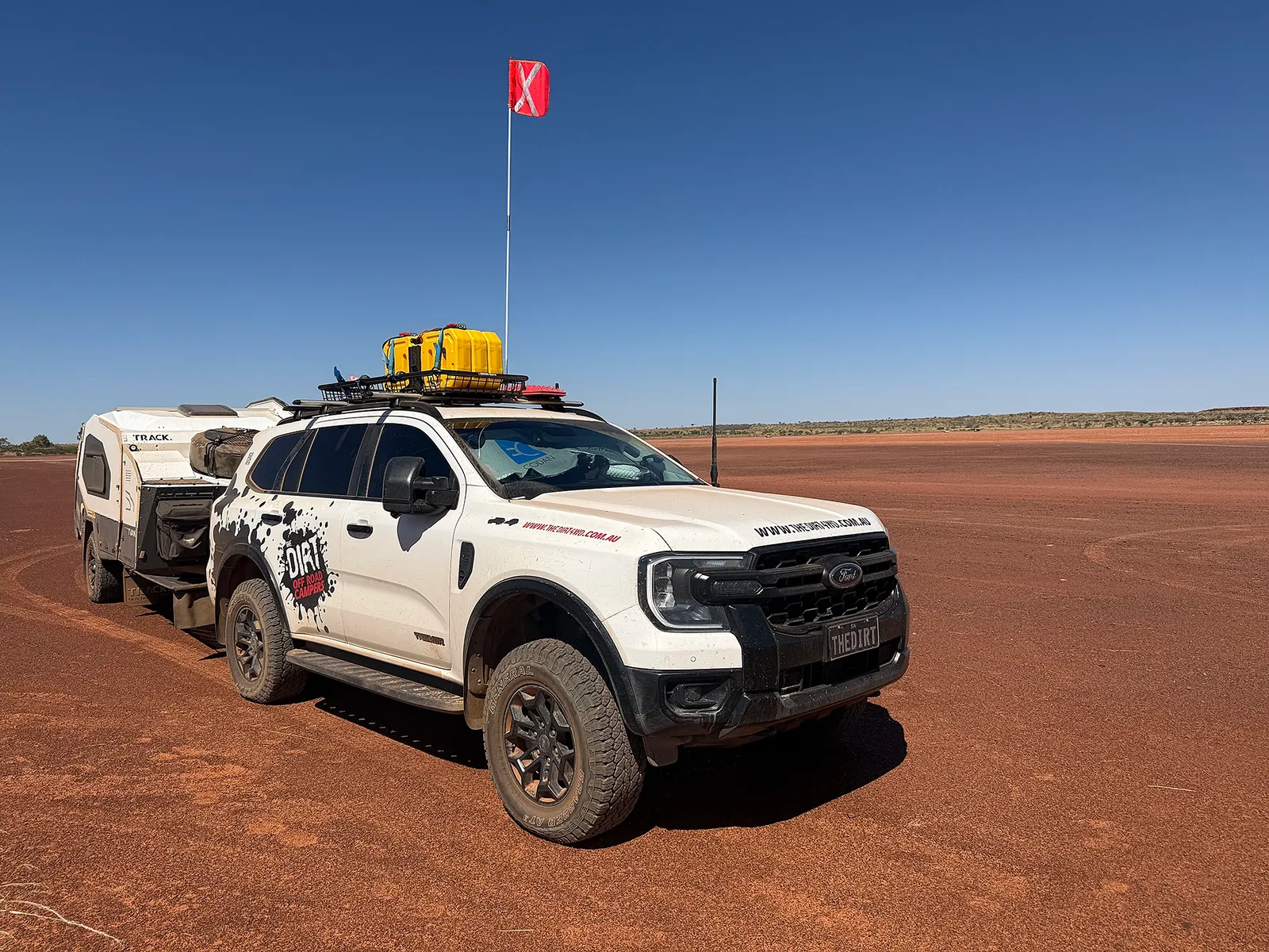 Ford Everest Tremor towing a Track Trailer Mk6 Tvan across a broad red salt pan, with a sand flag raised